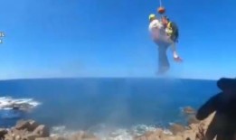 直升机机组人员用绞车把妇女吊到安全地带